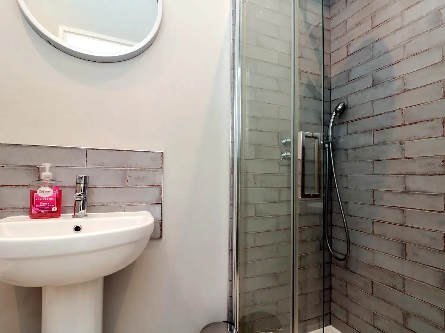 Modern en-suite shower with tiled walls and glass screen