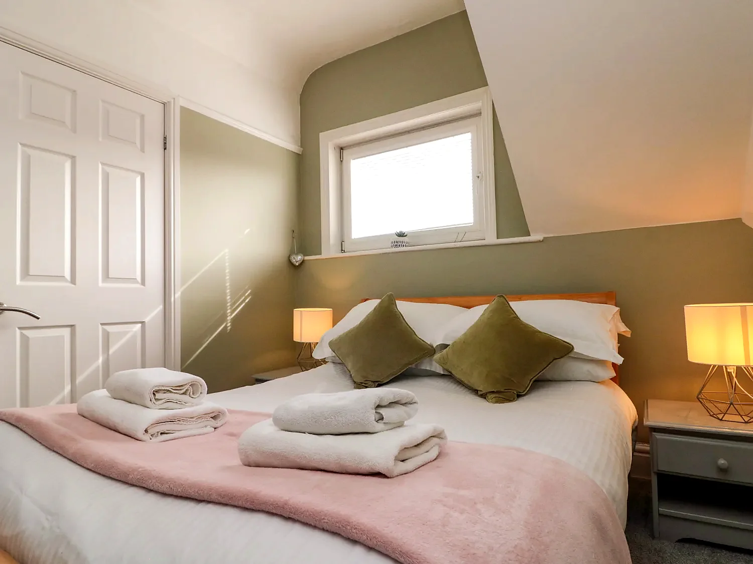 Bedroom with a neatly made bed and warm bedside lighting