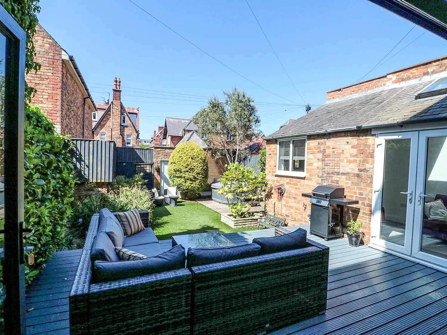 Decked outdoor seating area beside the enclosed lawn and garden