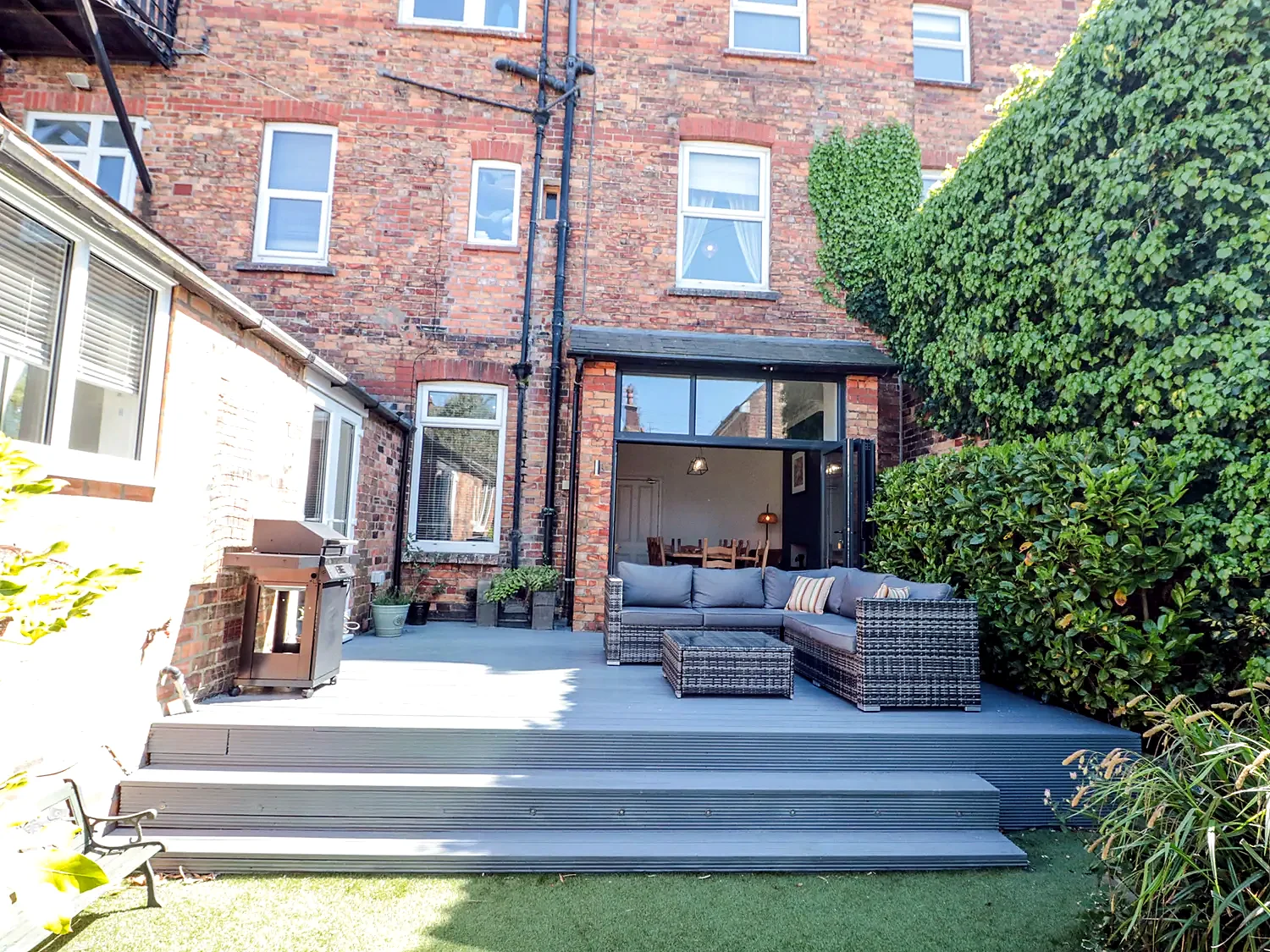 Enclosed garden patio with outdoor sofa seating and steps to the house