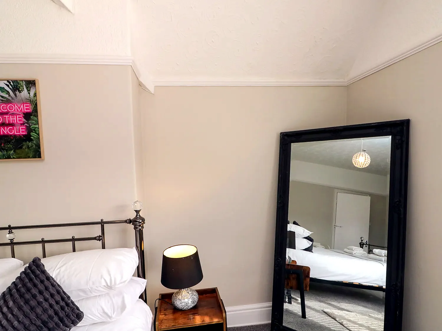 Guest bedroom with a comfortable bed, bedside table and mirror